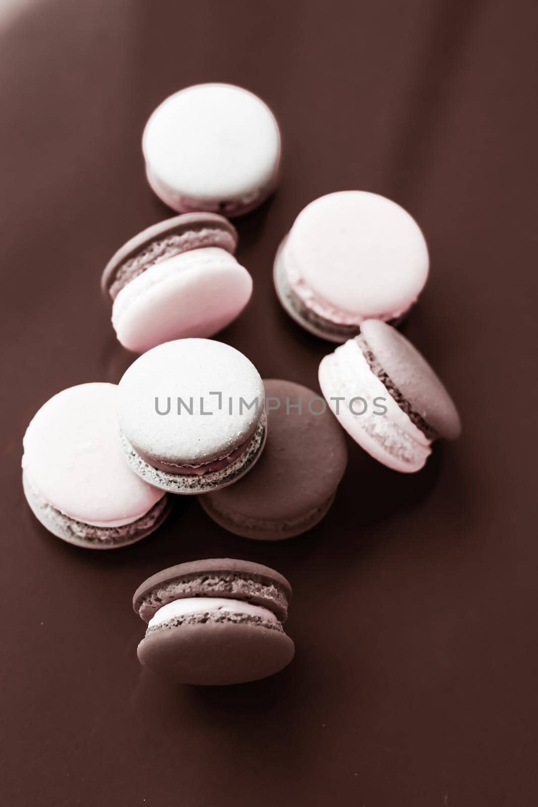 Pastry, bakery and branding concept - French macaroons on milk chocolate background, parisian chic cafe dessert, sweet food and cake macaron for luxury confectionery brand, holiday backdrop design