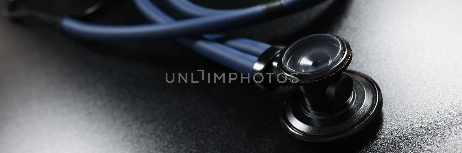 Close-up of doctor stethoscope equipment on dark surface, tool for patient diagnostic. Instrument to listen heartbeat and breath. Medicine, health concept