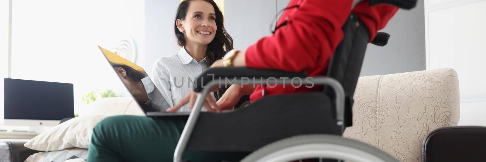 Portrait of friends spend time together watching movie on laptop, disabled woman in wheelchair hold device on lap. Disability, sisterhood, pastime concept