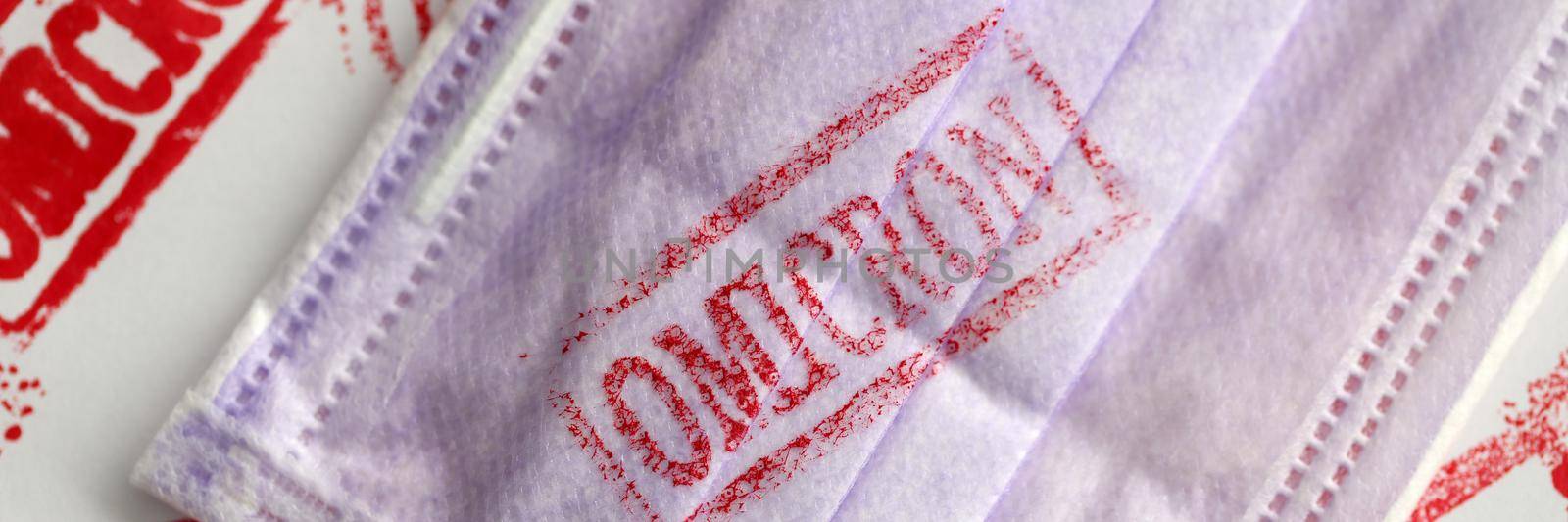 Protective medical face mask with omicron virus infection stamp closeup by kuprevich