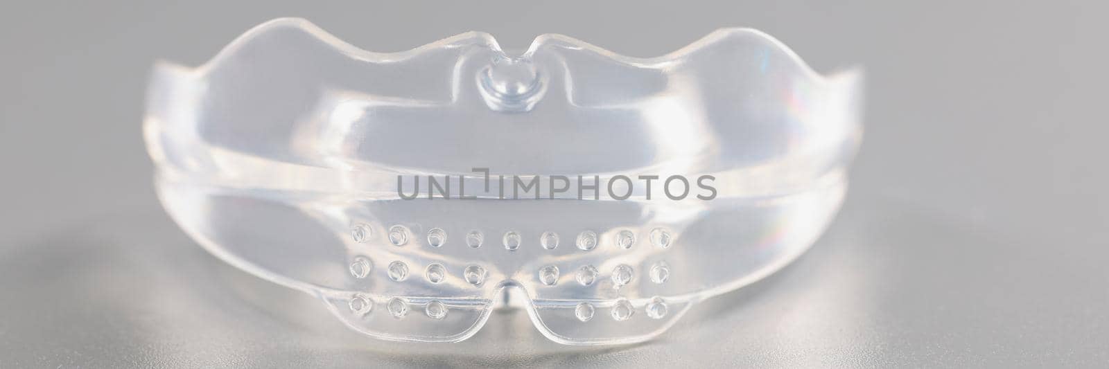 Close-up of transparent piece of mouthpiece, equipment to wear for teethcare. Instrument for correcting bite. Medicine, stomatology, dental care concept