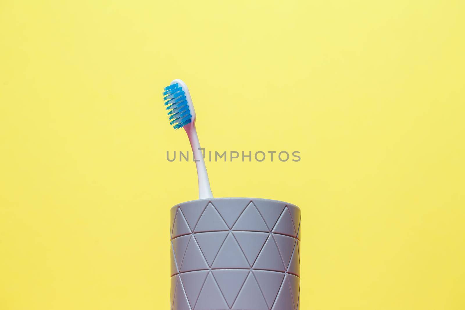 A blue toothbrush is standing in a gray glass. Dental care concept