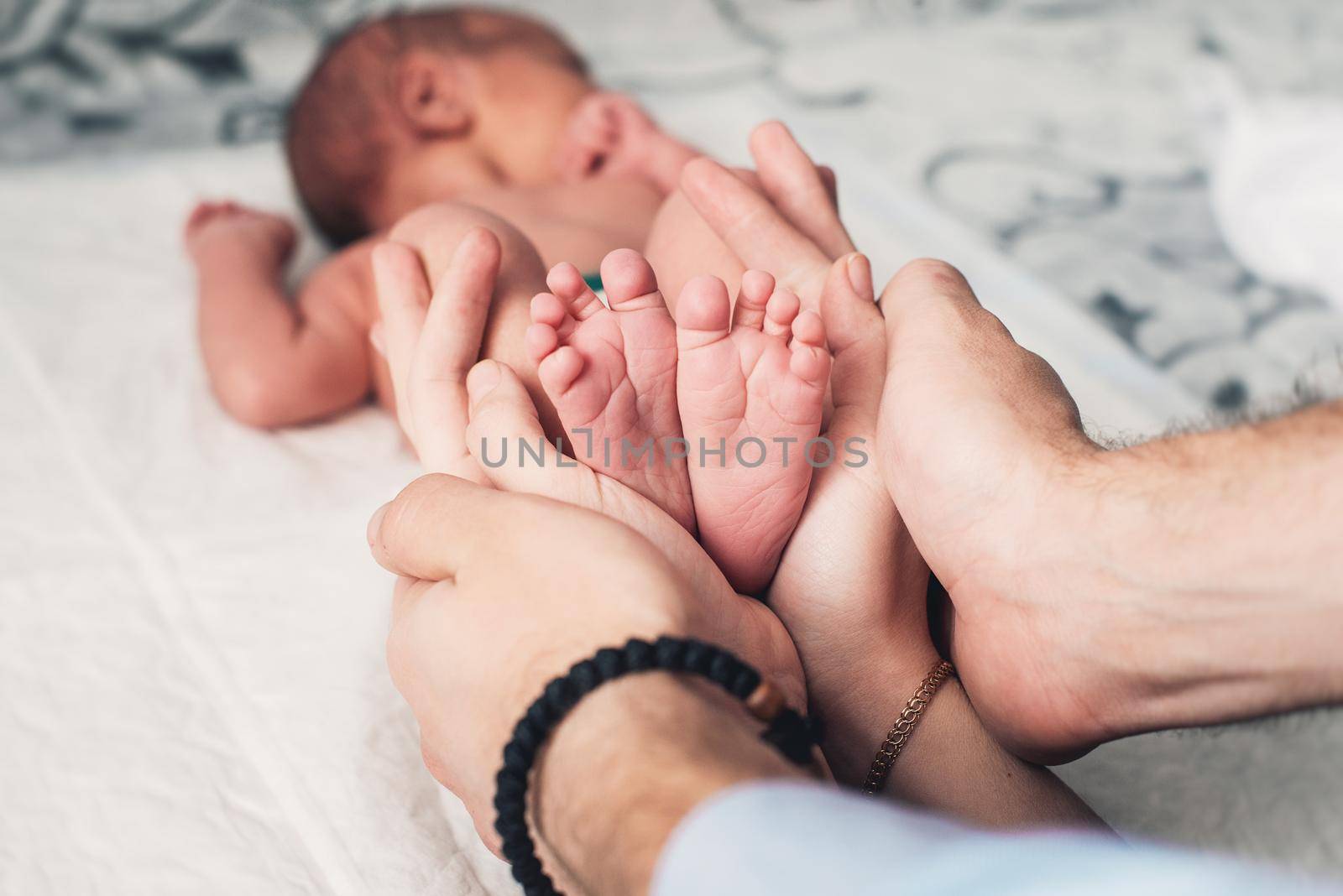 Baby feet in mother and father hands. Tiny Newborn Baby's feet on female Heart Shaped hands closeup. Mom, dad and their Child. Happy Family concept. Beautiful conceptual image of Maternity