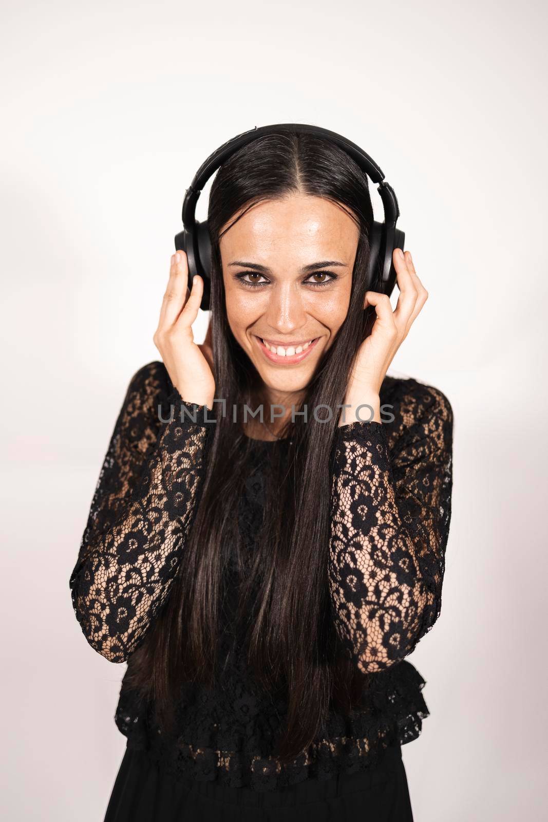 A young elegant female musician looking at camera listening to some music by stockrojoverdeyazul
