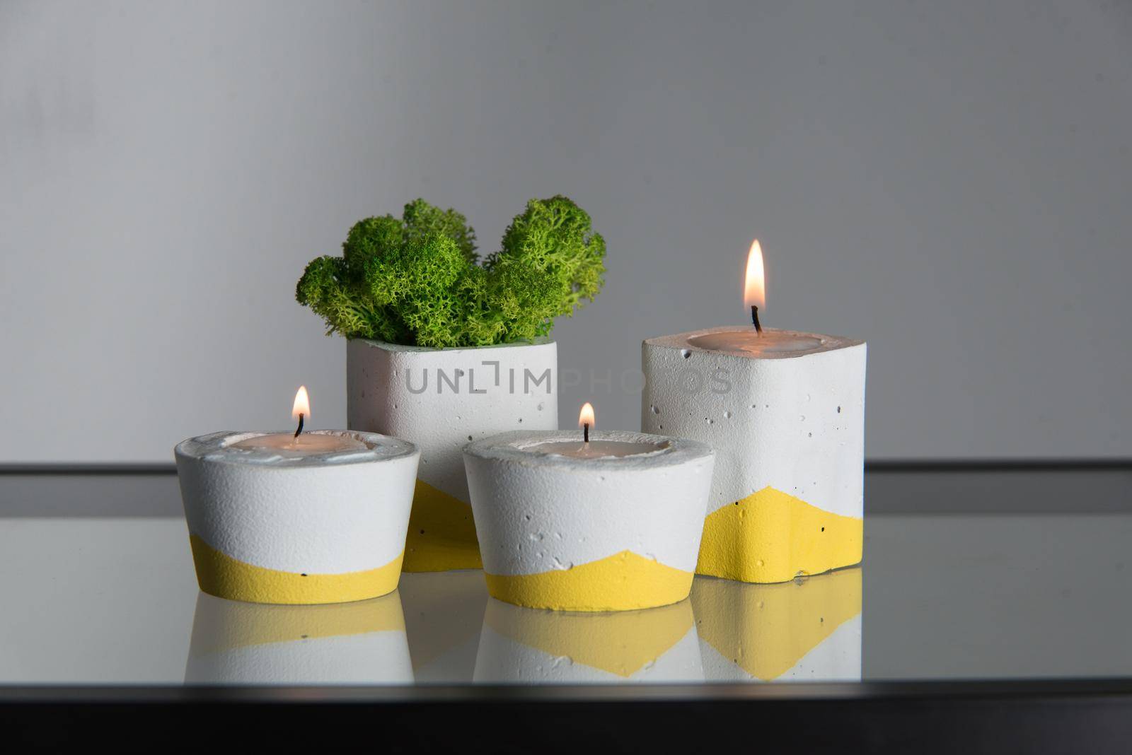 candles and moss in white and yellow concrete candle holders.