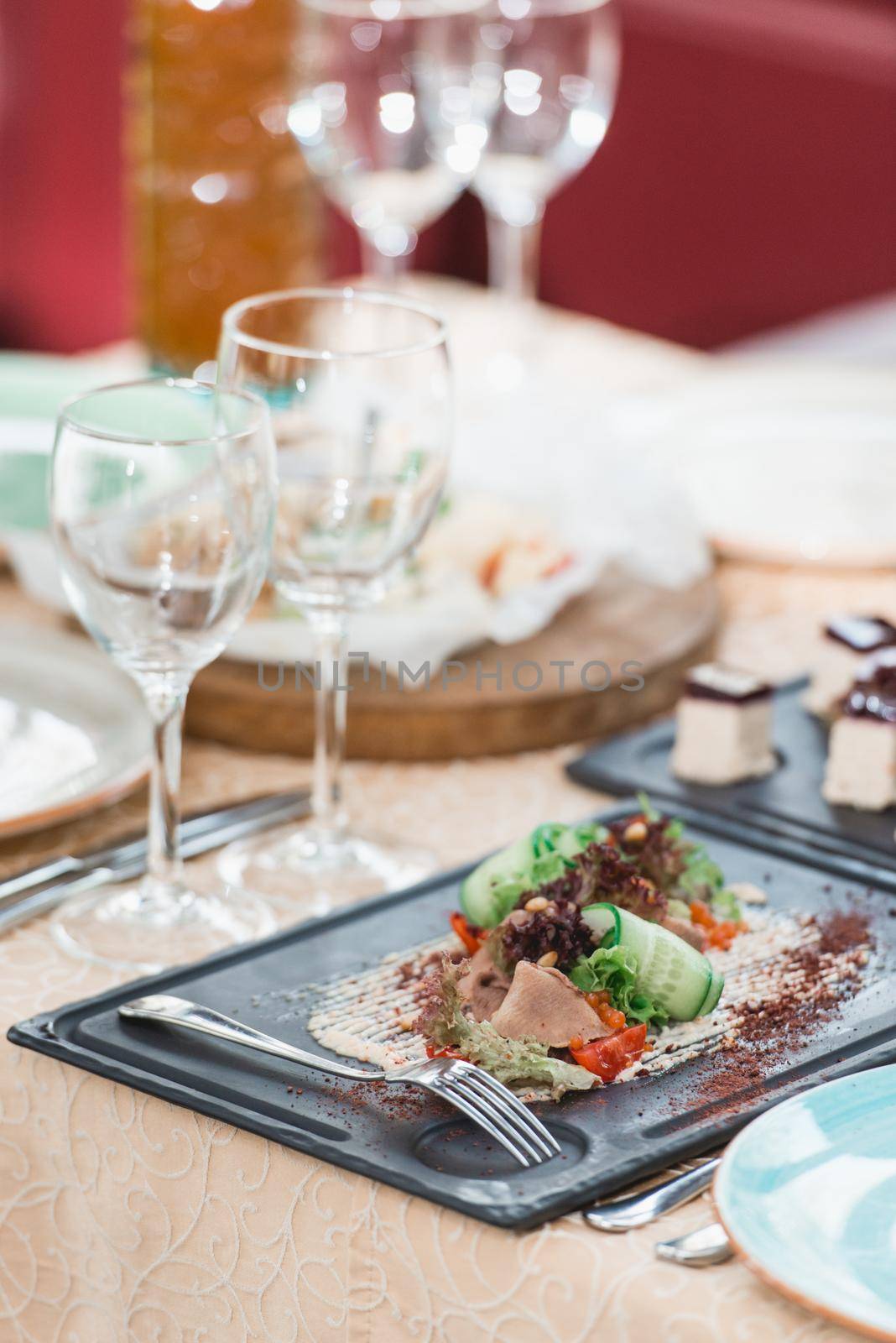 delicious meat salad on stone plate side view on black stone plate. Served table in a restaurant.