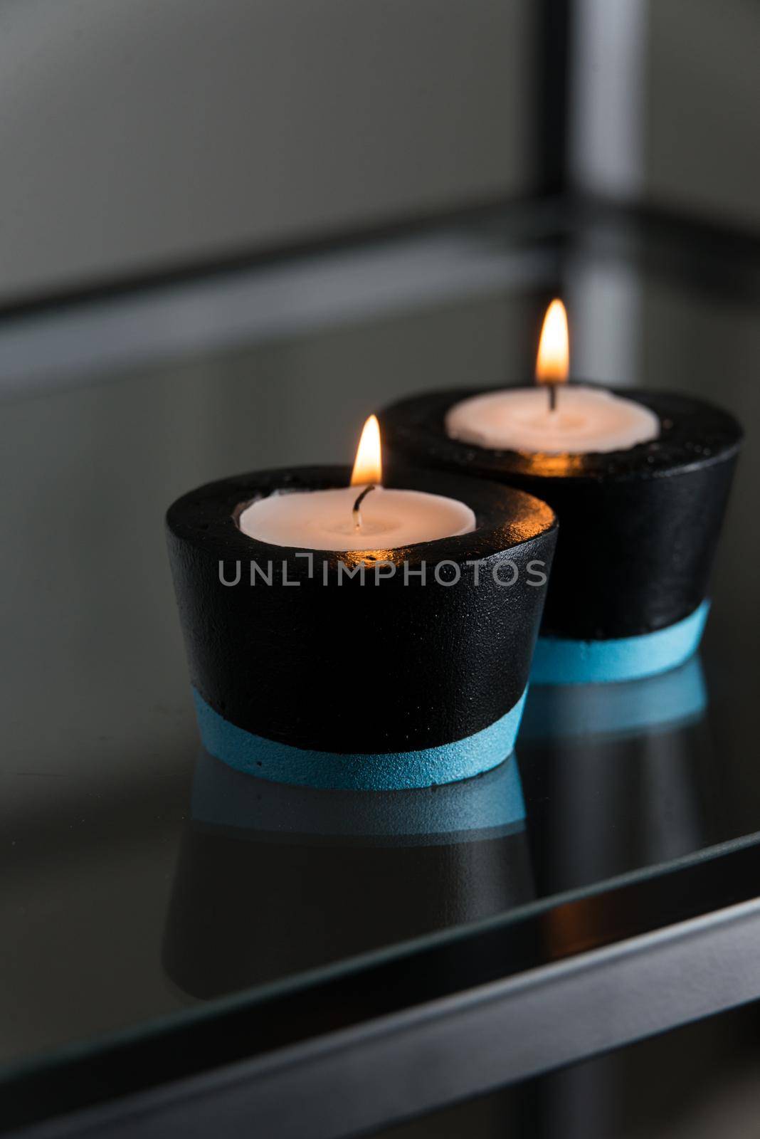 Candles in black and blue concrete candle holders.