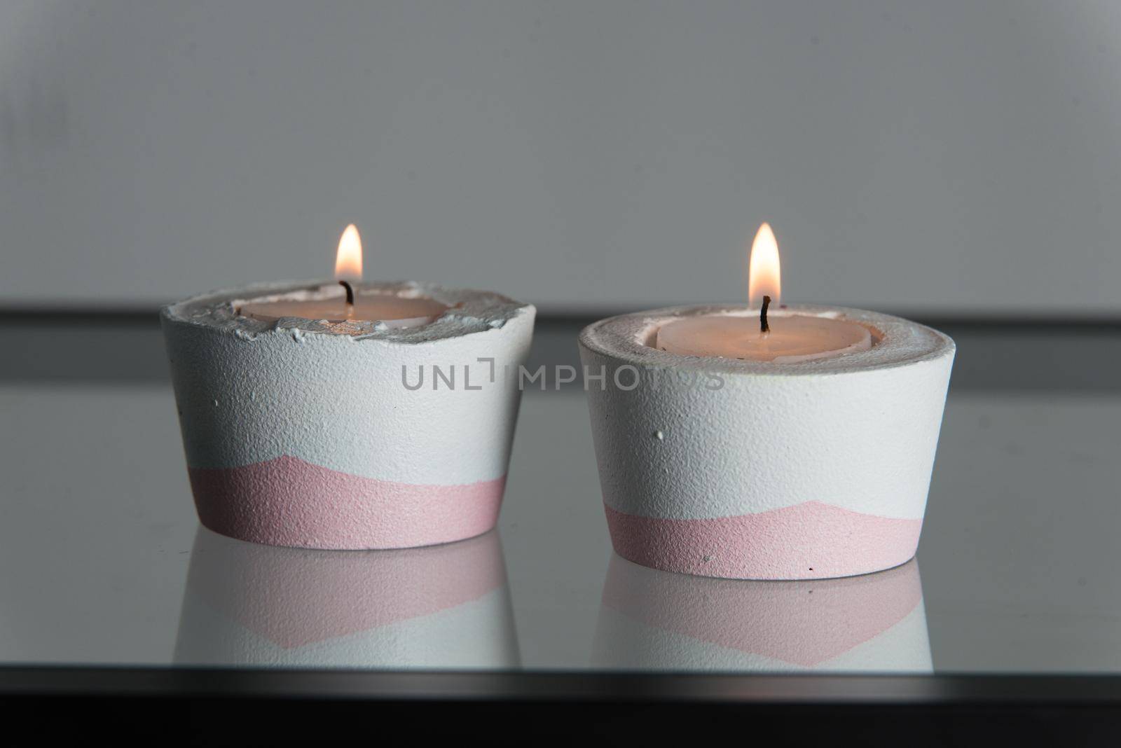 Two candles in white and pink concrete candle holders by Ashtray25