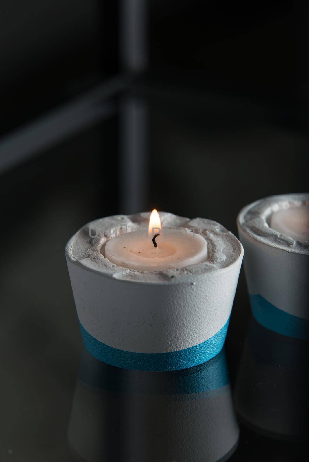 Two candles in white and blue concrete candle holders.