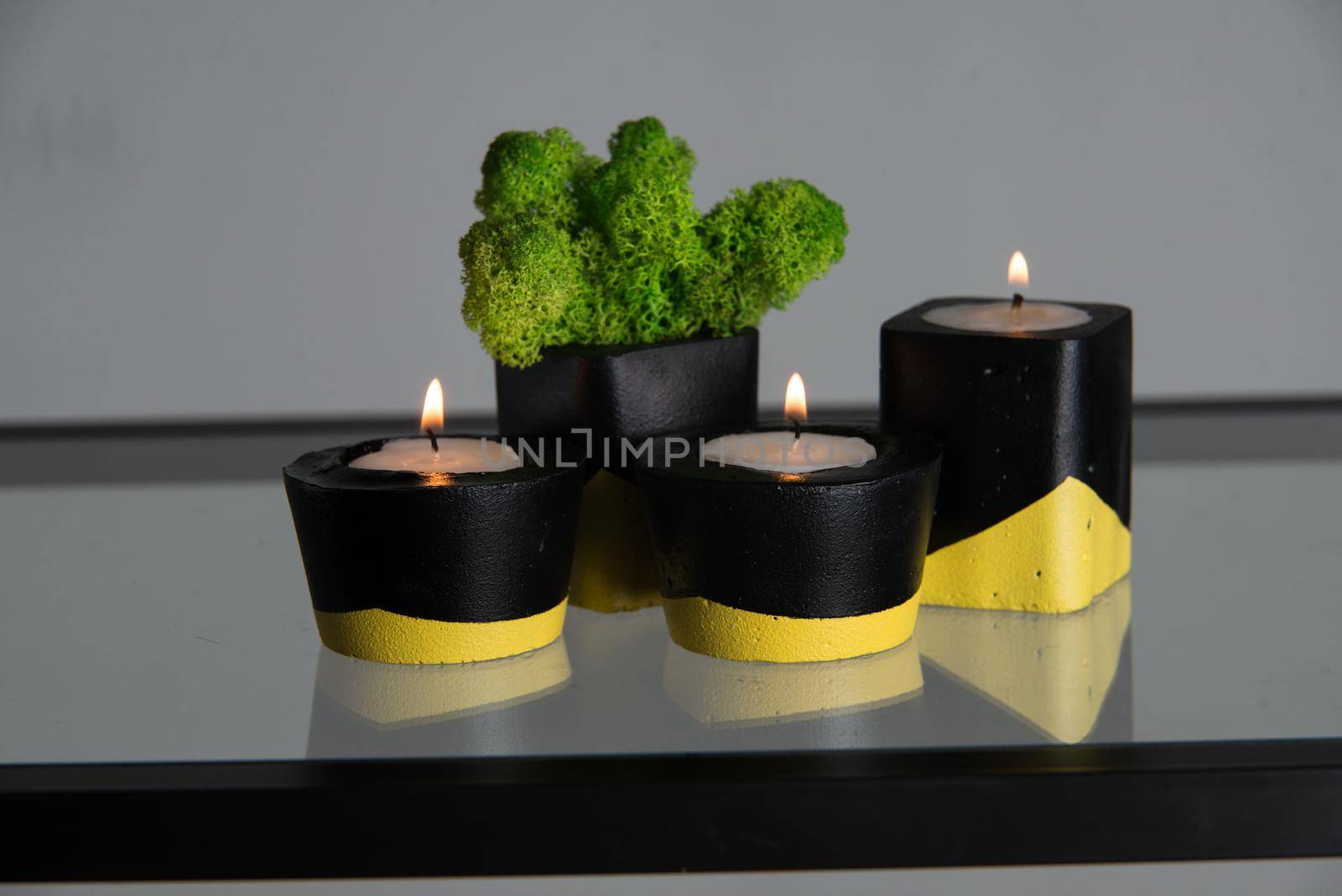 candles and moss in black and yellow concrete candle holders.