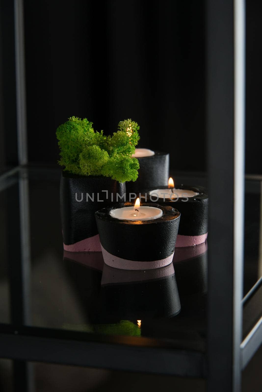 candles and moss in black and pink concrete candle holders.