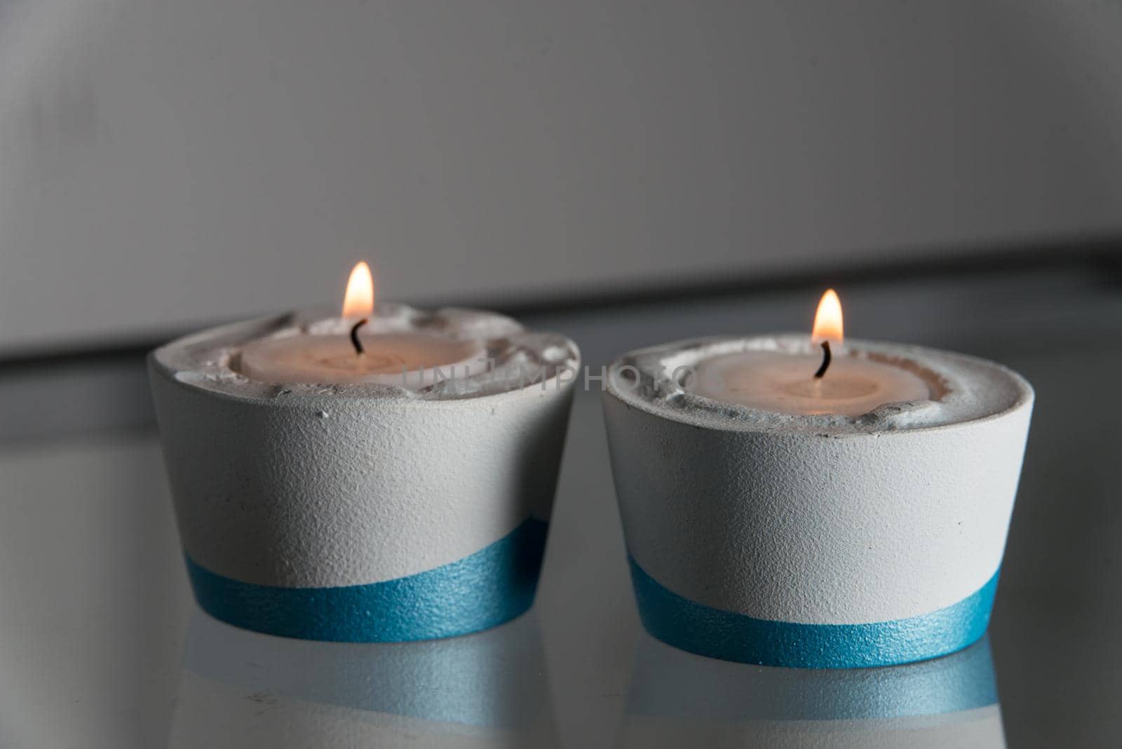 Two candles in white and blue concrete candle holders.