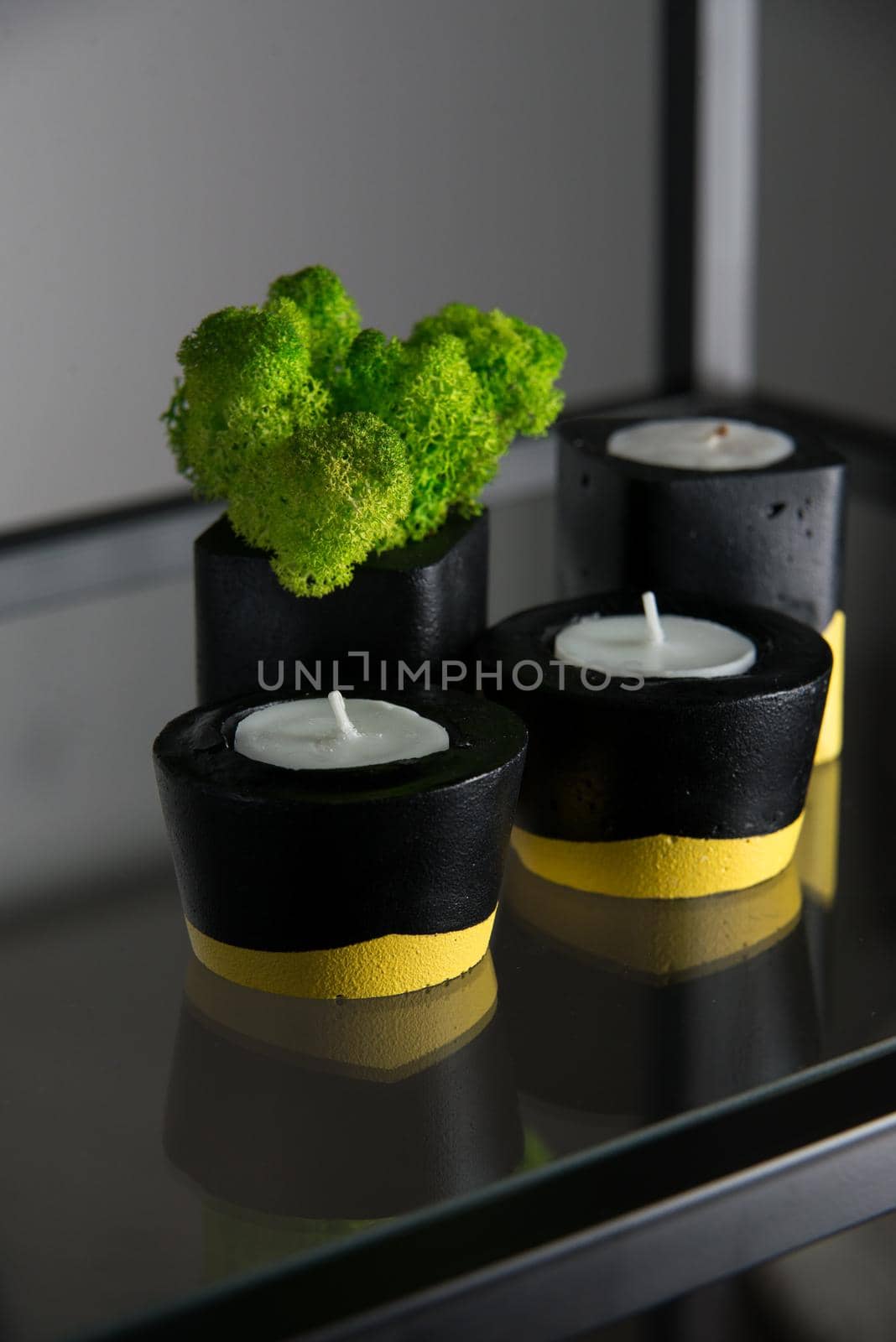 candles and moss in black and yellow concrete candle holders.