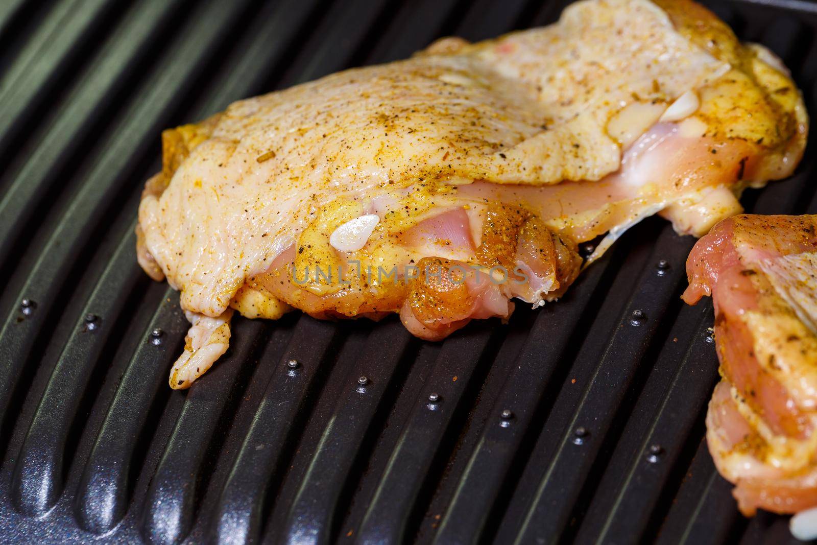 grilling chicken with spices on the electric grill in the home kitchen