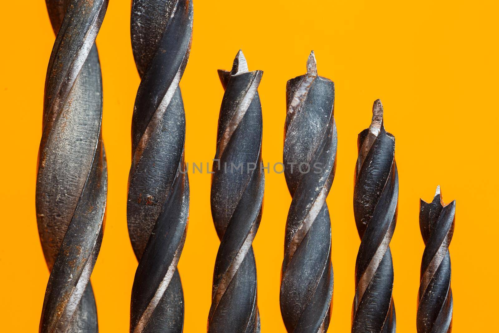 Drills for wood of different sizes for a drill on an orange background. Construction tool