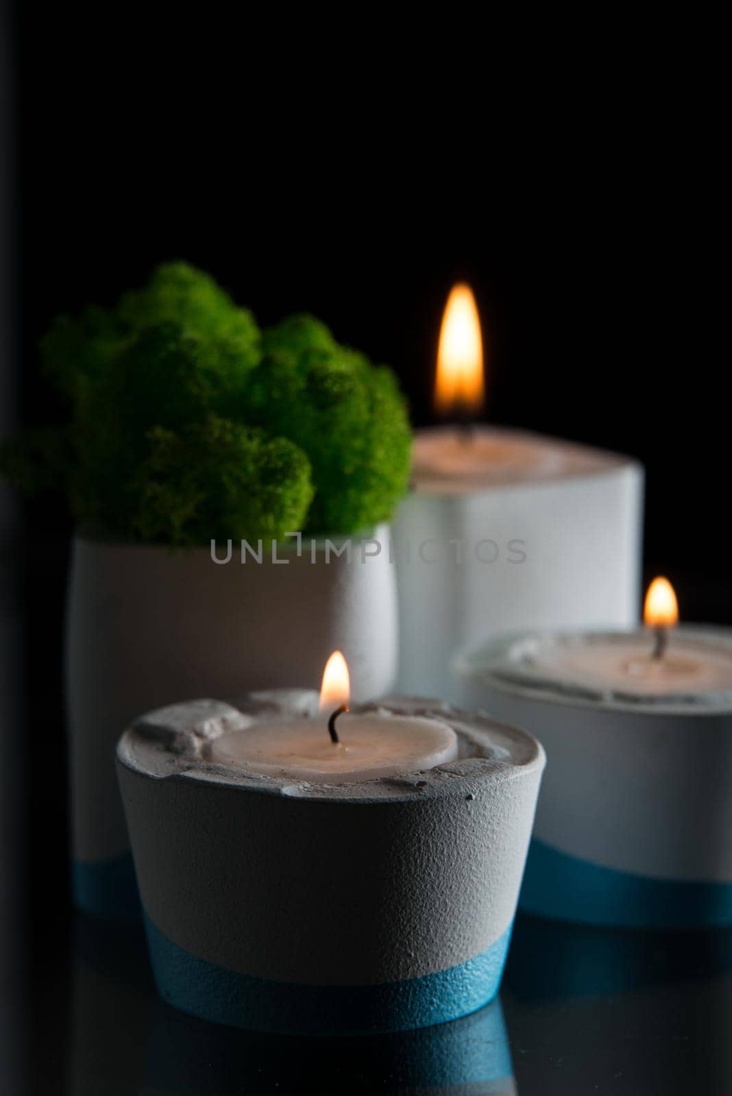 candles and moss in white and blue concrete candle holders.