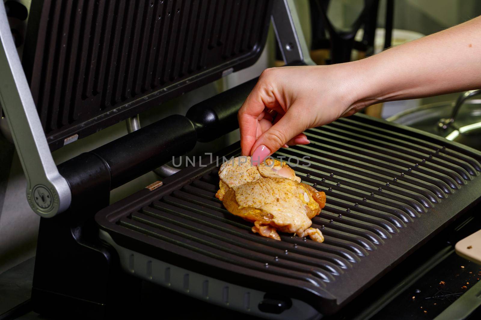 grilling chicken with spices on the electric grill in the home kitchen