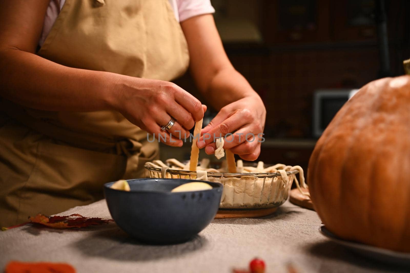 Close-up of housewife decorating the festive homemade pumpkin apple pie with a crunchy pastry lattice. Thanksgiving Day by artgf