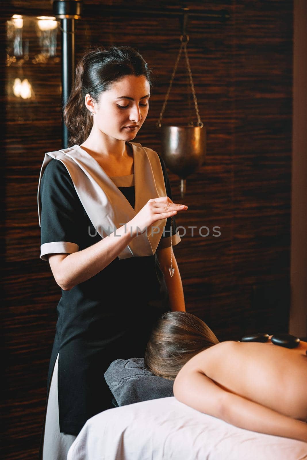 Young charming girl on a panchakarma procedure laying on a massage table. beautiful woman spending time at modern spa cabinet relaxing. Soft yellow light by Ashtray25