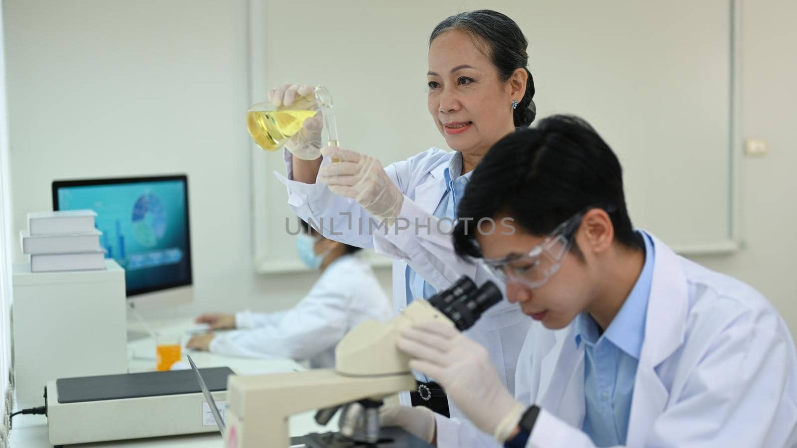 Senior female scientist in white coat examining samples and liquid in laboratory. Medicine and science researching concepts.