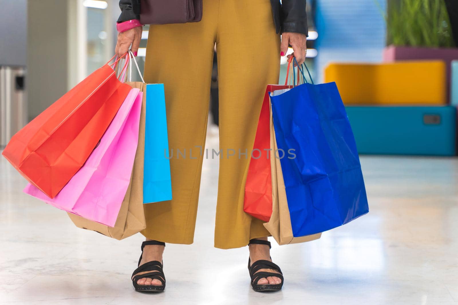 Unrecognizable woman with colorful shopping bags in the mall. High quality photo