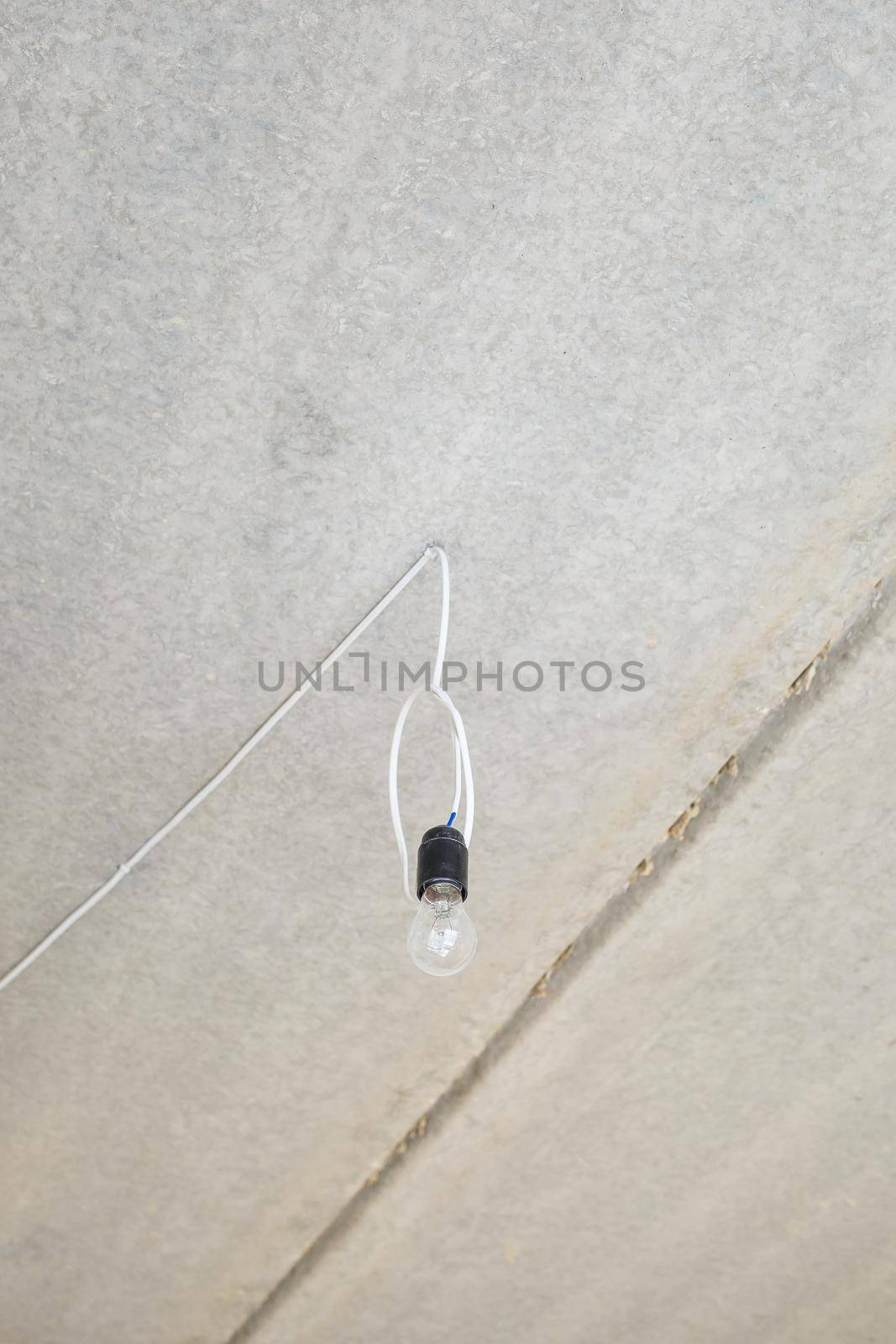 Light bulb on the ceiling. Lonely light bulb and wire sticking out of the ceiling during a repair