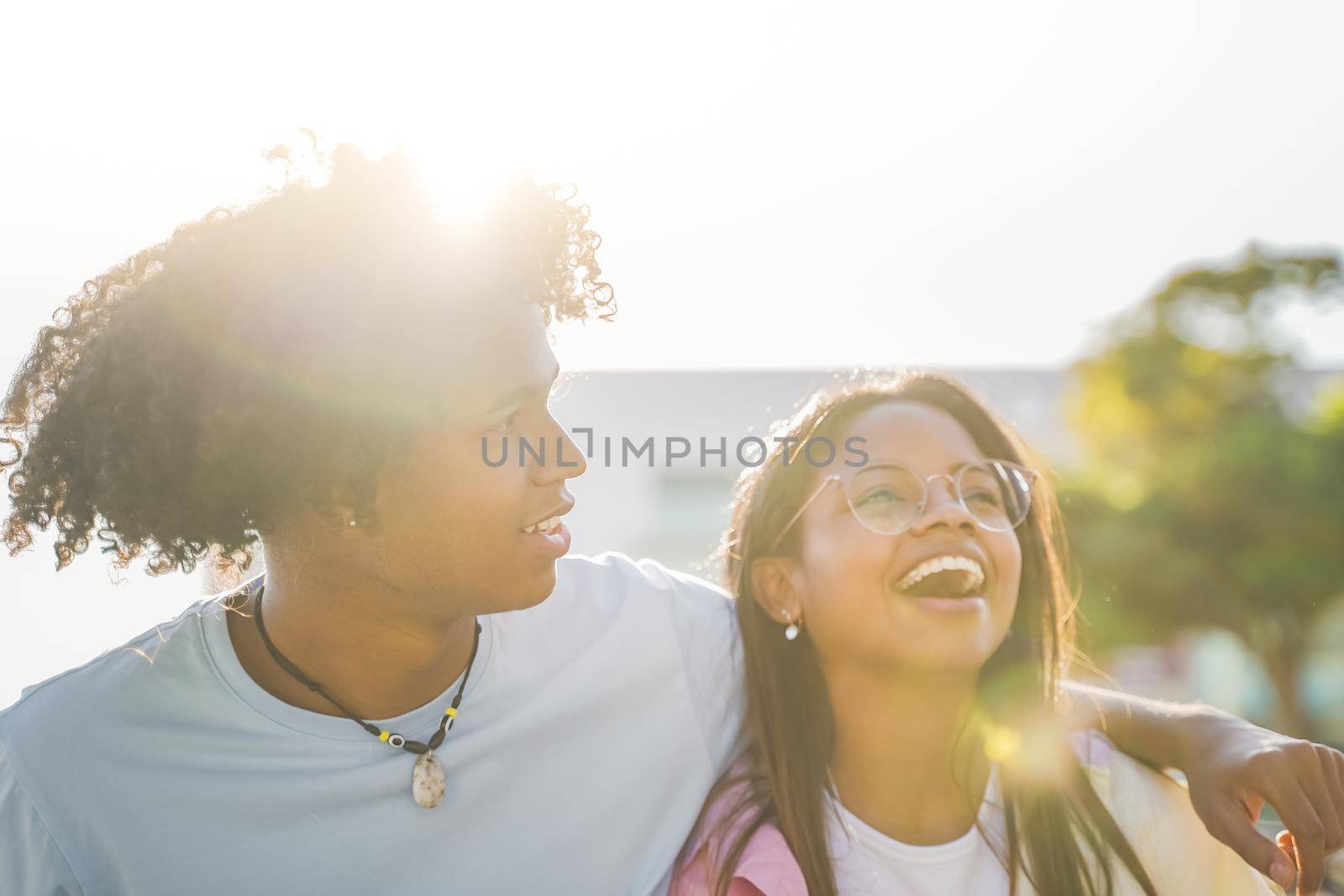 Happy hispanic and African American couple laughing and cuddled with love during sunset in the city. Love concept. High quality photo