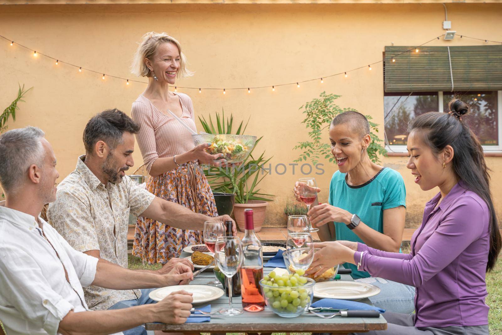 Mature happy friends dining together in barbecue dinner party in summer. Smiles, cheerfulness concept. by PaulCarr