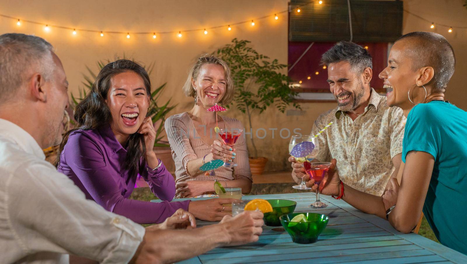 Cheerful friends drinking cocktails. Mature people having fun summer night. Lifestyle and nightlife concept. by PaulCarr