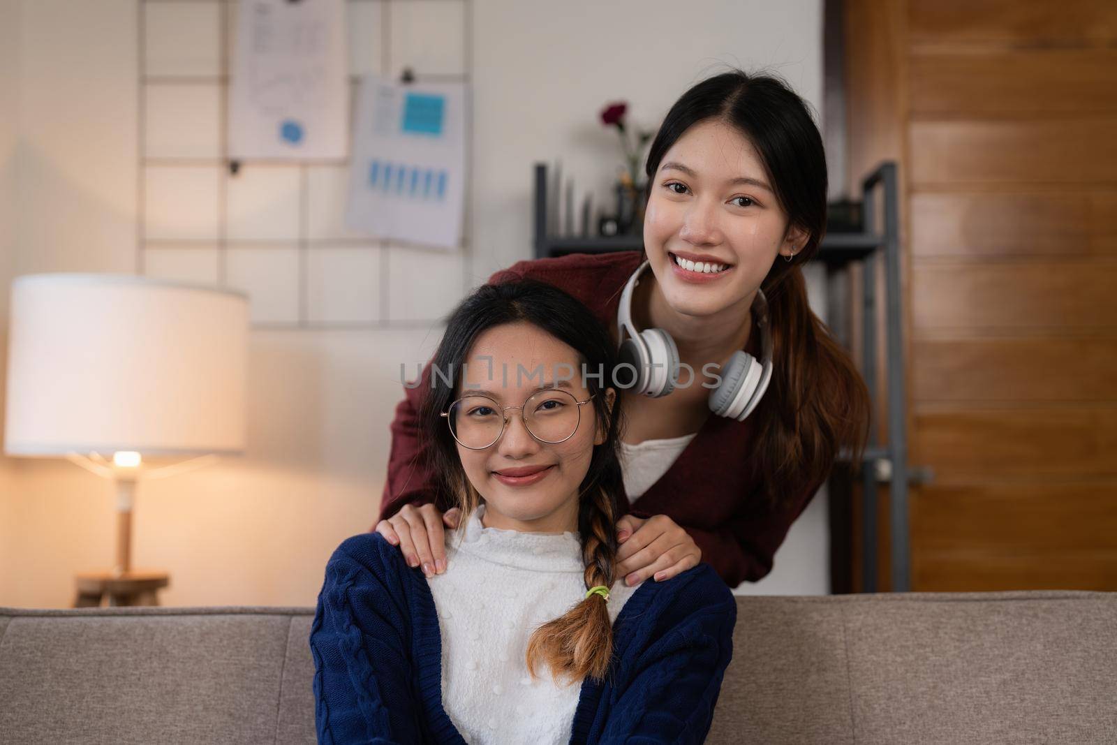 Two asian women having nice lively activity in living room on sofa in cozy interior by itchaznong