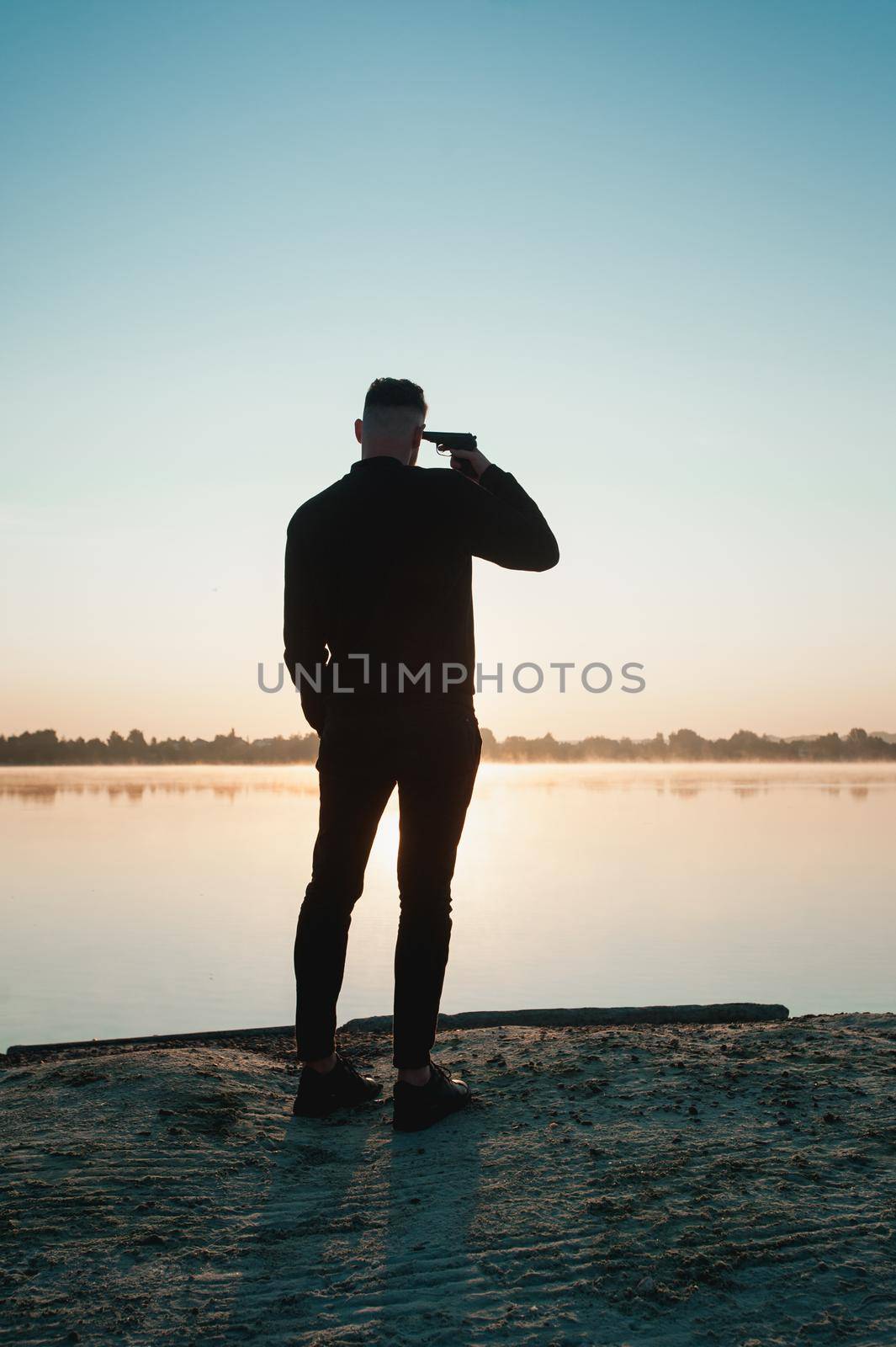 Suicide minds. Depressed young man holding gun near his head standing near water by Ashtray25