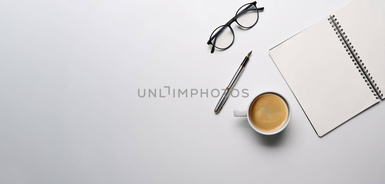 Top view empty notebook, eyeglasses and coffee cup on white background.