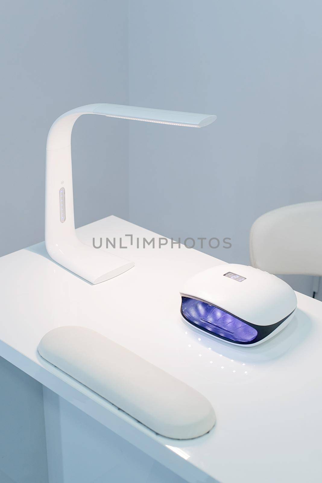 Manicure Studio. White lamp on white table with nail tool