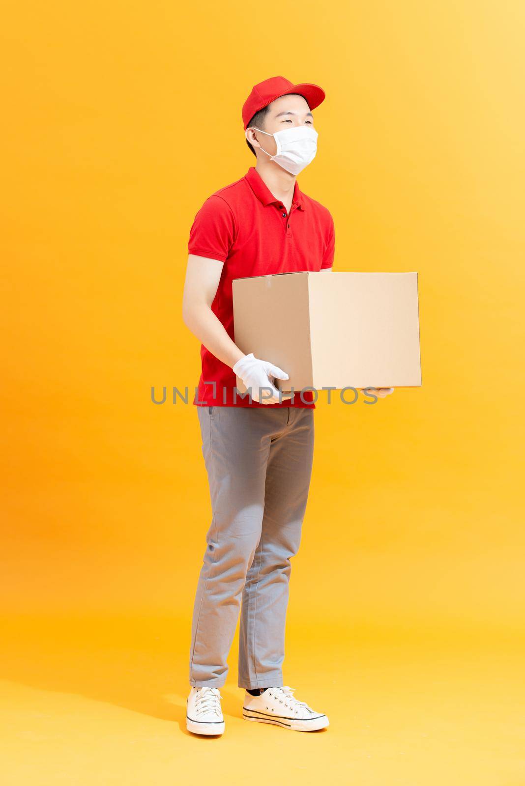 Home delivery, online order. Male courier in a medical mask and  gloves with a parcel in his hands