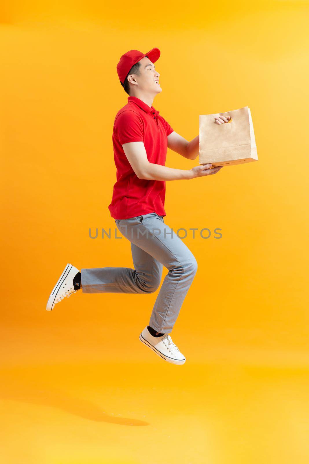 Delivery man in red uniform hold craft paper packet with food  by makidotvn