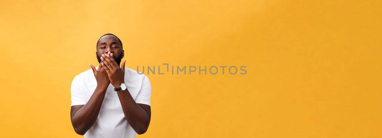 Portrait of african american man with hands raised in shock and disbelief. Isolated over yellow background