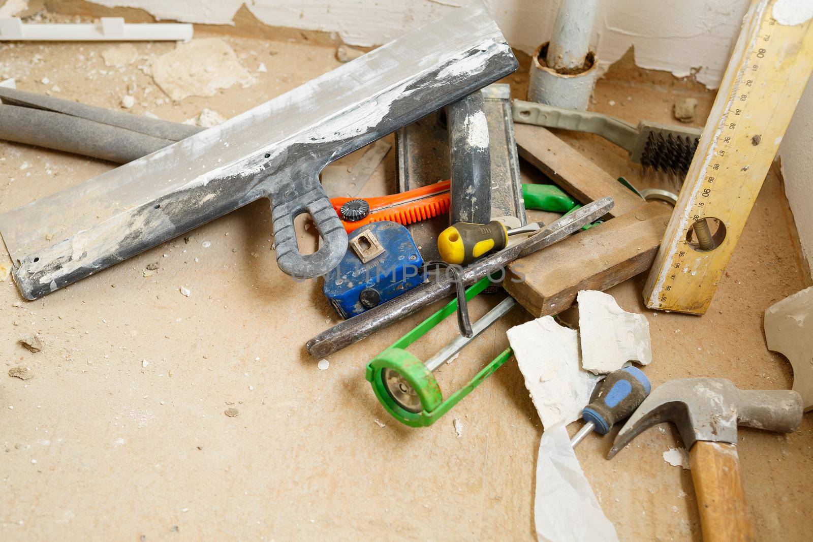 Tools for construction and repair lie on the concrete floor during repair work with a spatula, hammer, tape measure. To make repairs. Selective focus