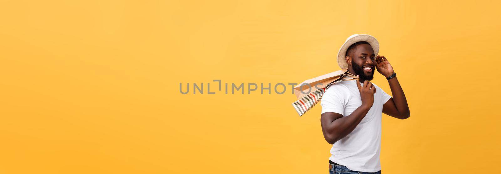 African American man with colorful paper bags isolated on yellow background.