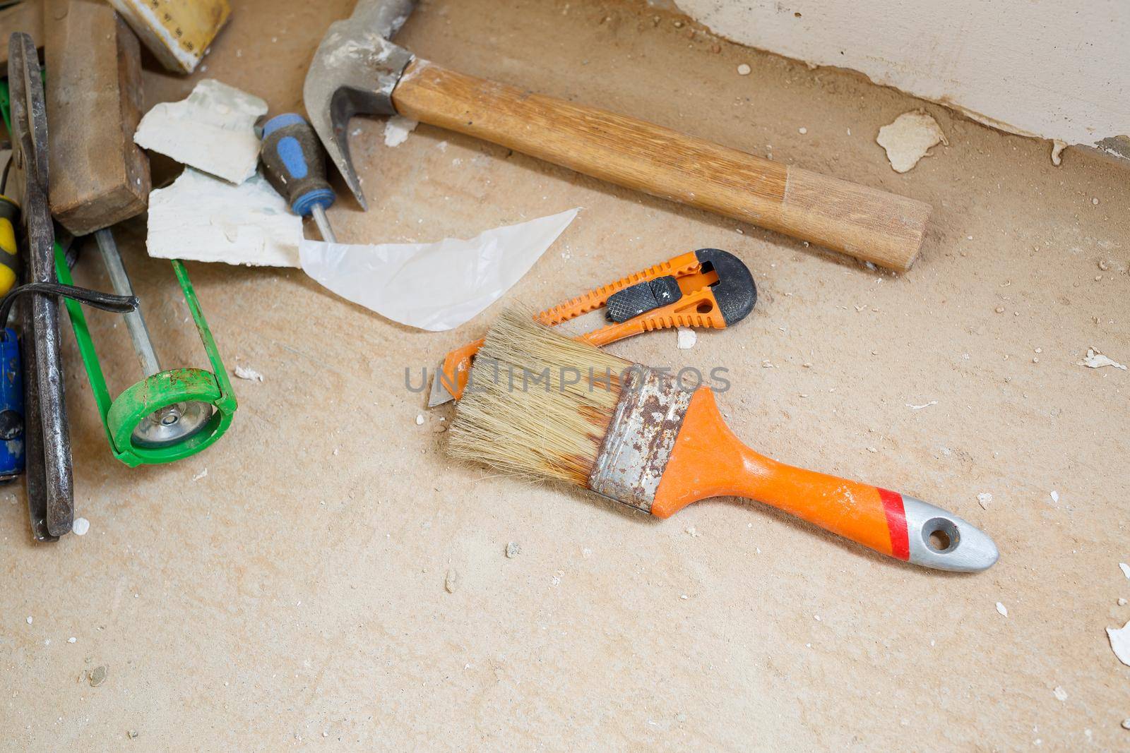 Tools for construction and repair lie on the concrete floor during repair work with a spatula, hammer, tape measure. To make repairs. Selective focus