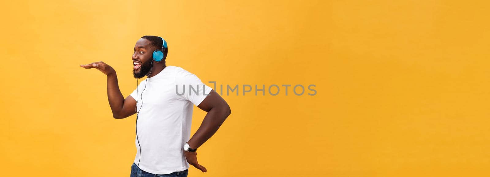 Young African American man wearing headphone and enjoy music dancing over yellow gold Background by Benzoix