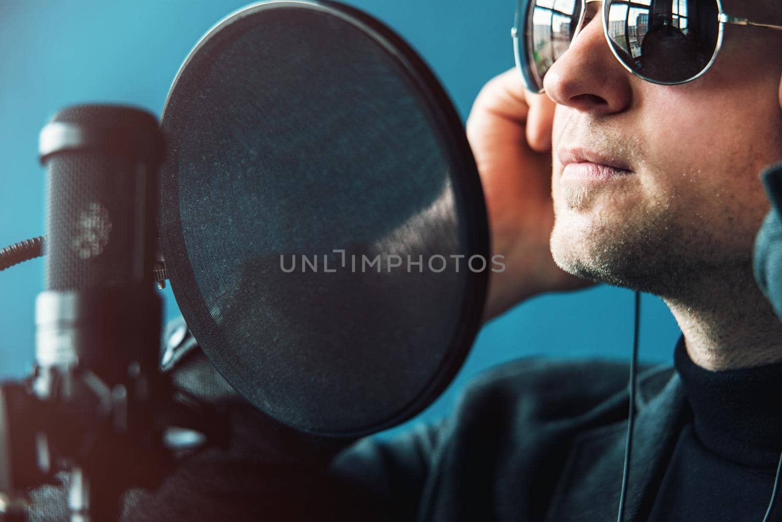 Close up of a man singer in a headphones recording a song in a home studio by Ashtray25