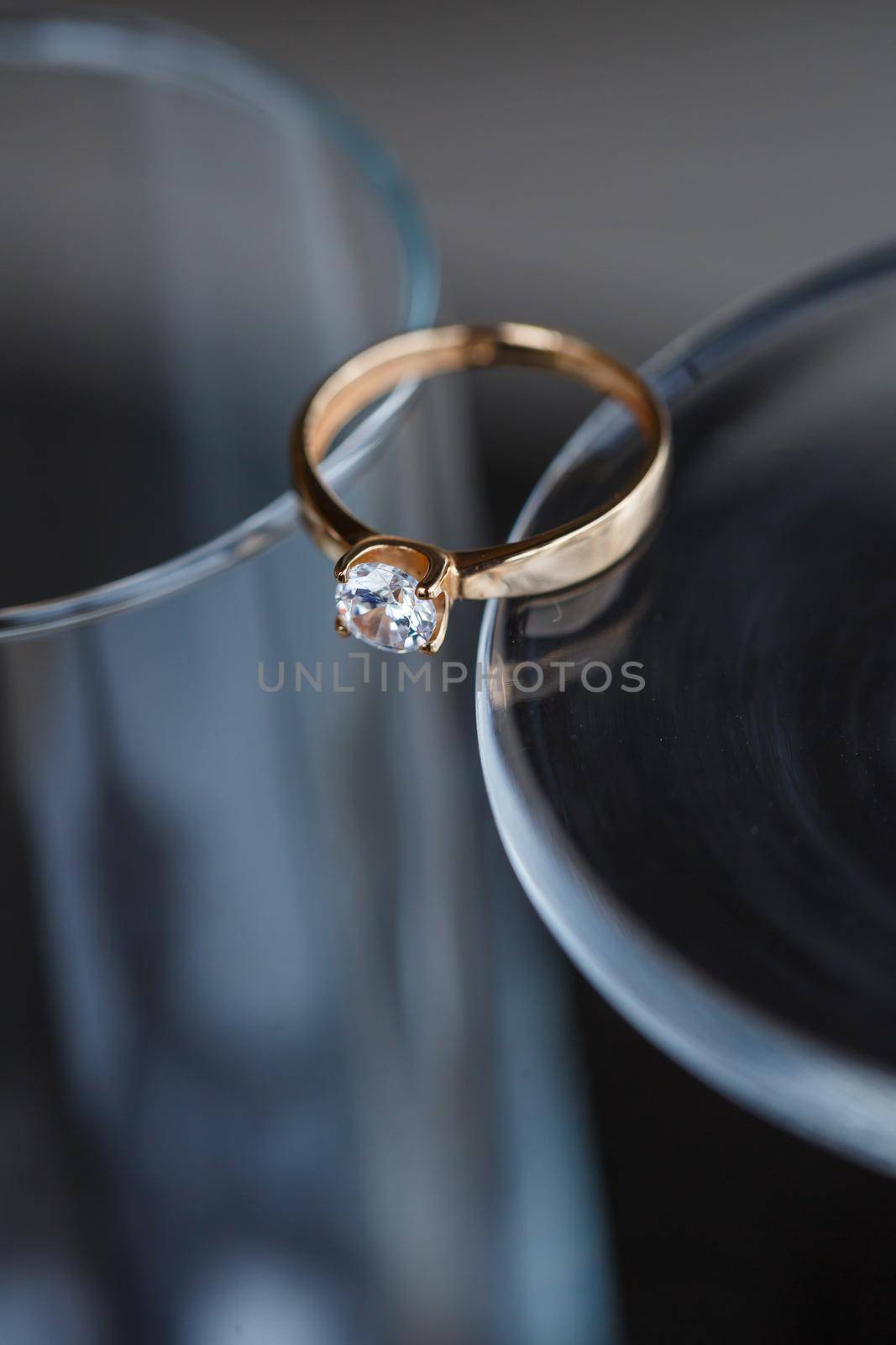 A wedding ring made of precious metal with a diamond stone lies in a glass