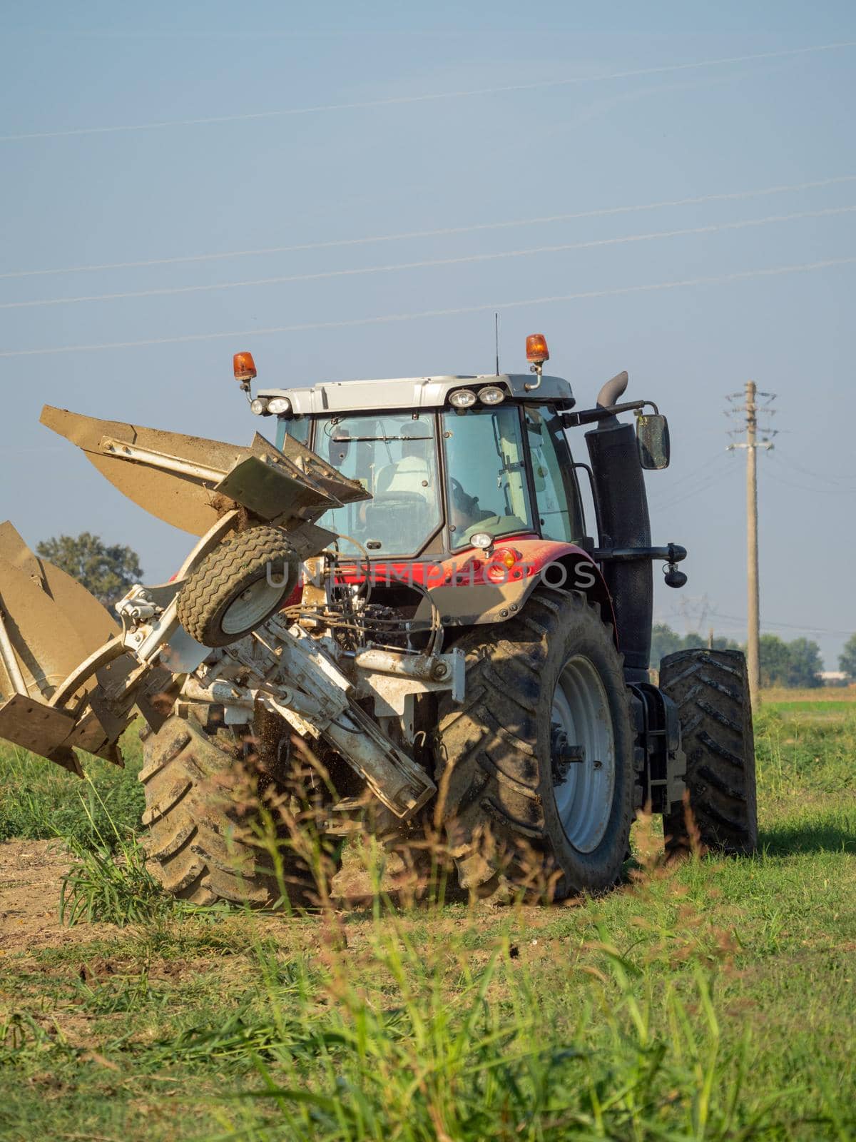 Farmer driving tractor plowing land at the end of the summer season by verbano