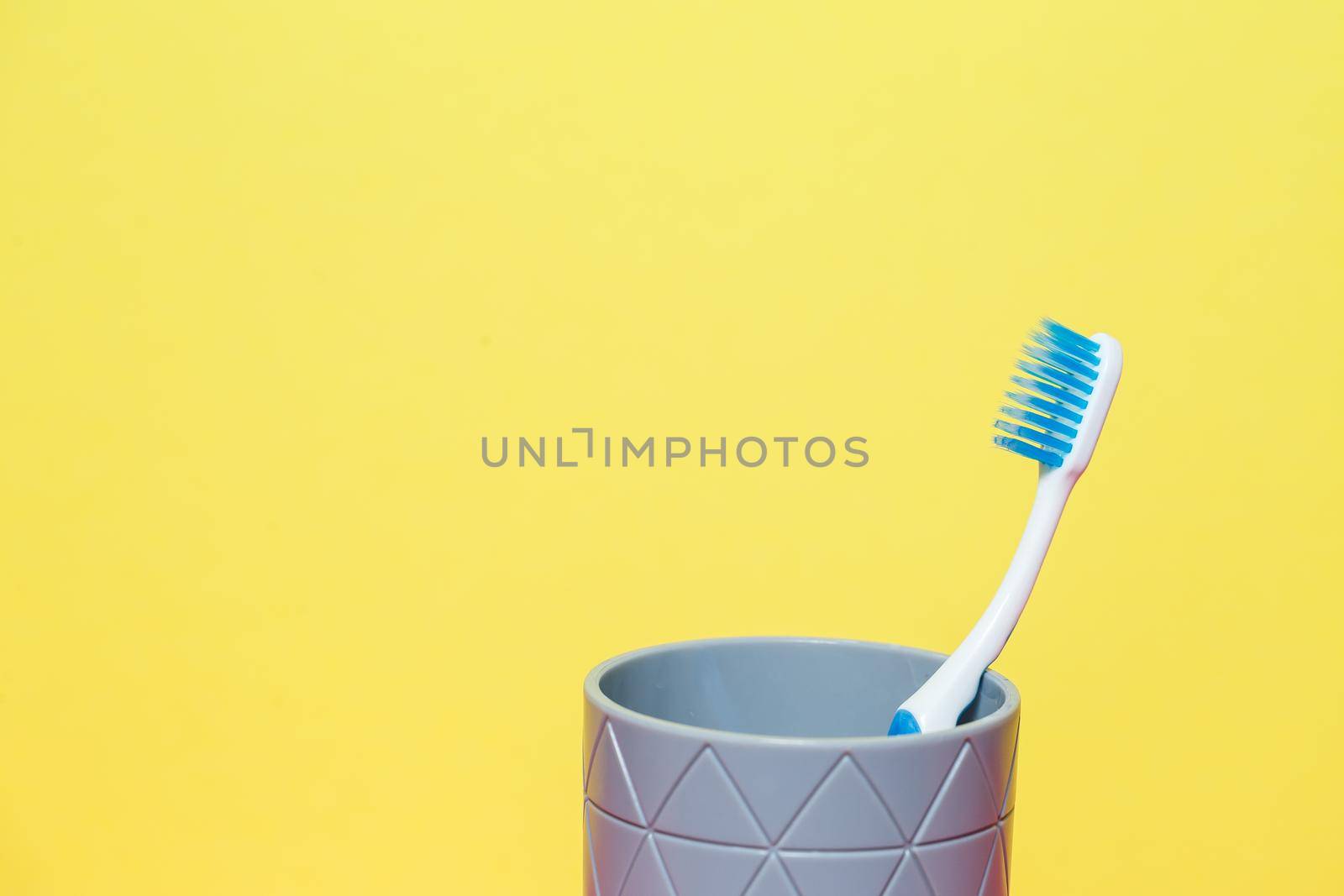 A blue toothbrush is standing in a gray glass. Dental care concept