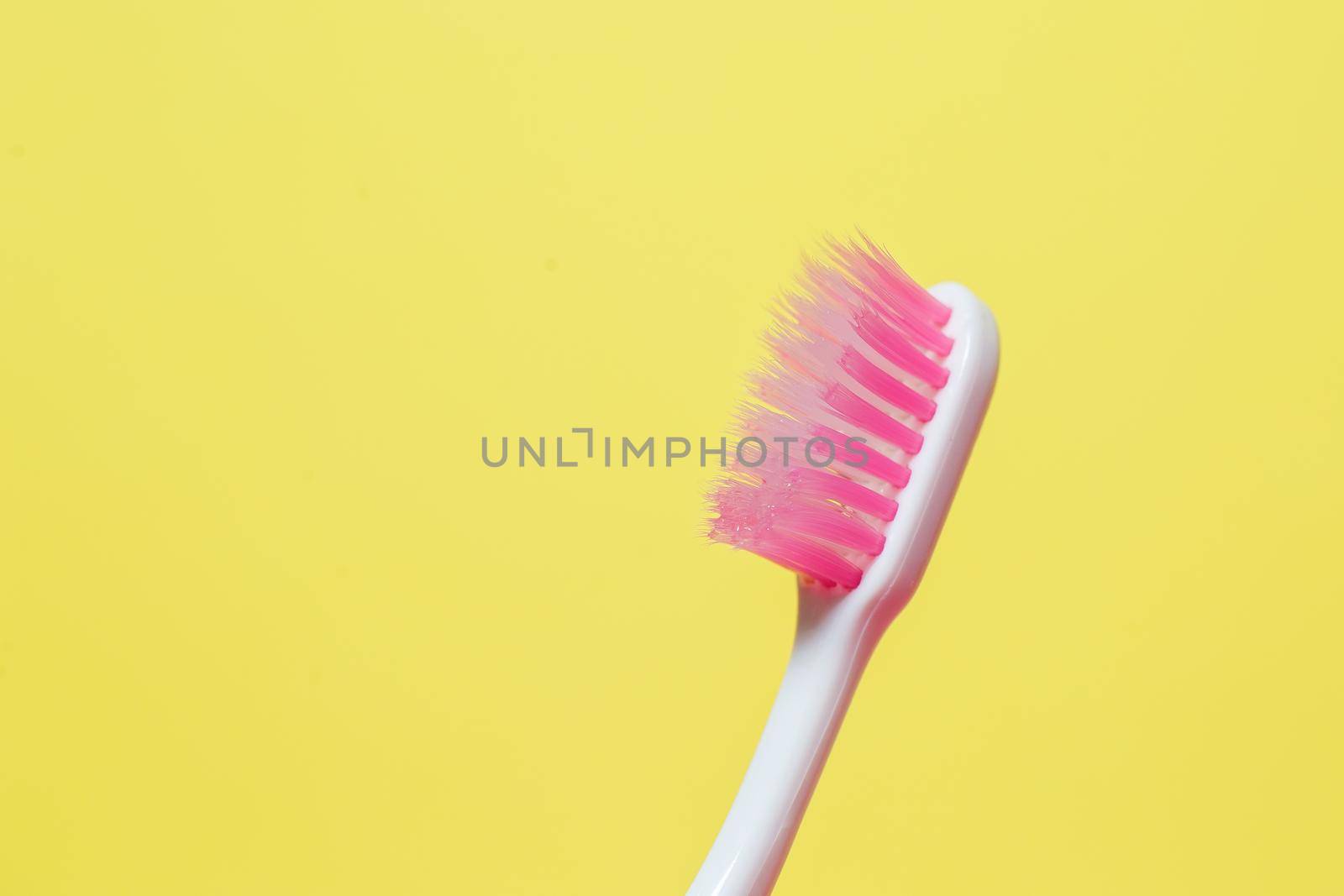 A pink toothbrush is standing in a gray glass. Dental care concept by Dmitrytph
