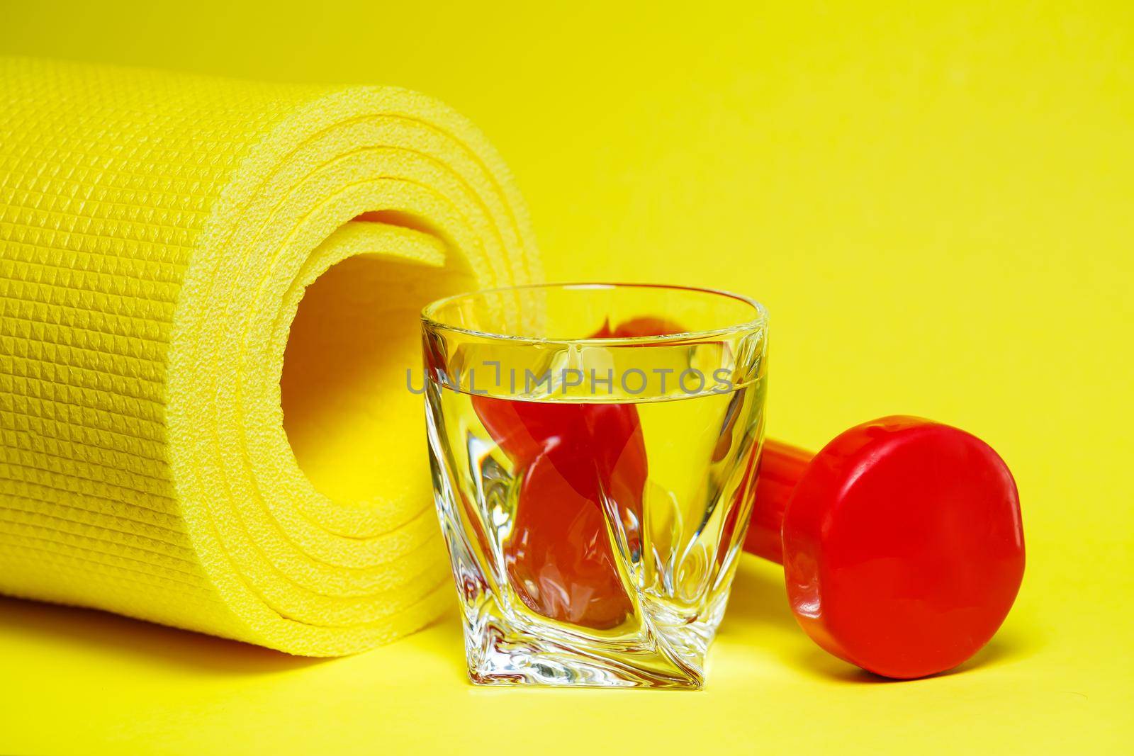 red dumbbells, a glass of water, a yellow rug, colored background, sports, energy drink, equipment for the gym