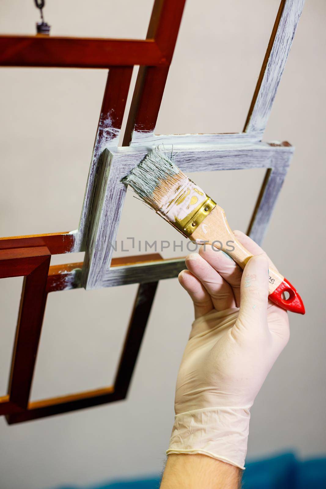 the master paints with a brush a wooden brown photo frame with light paint