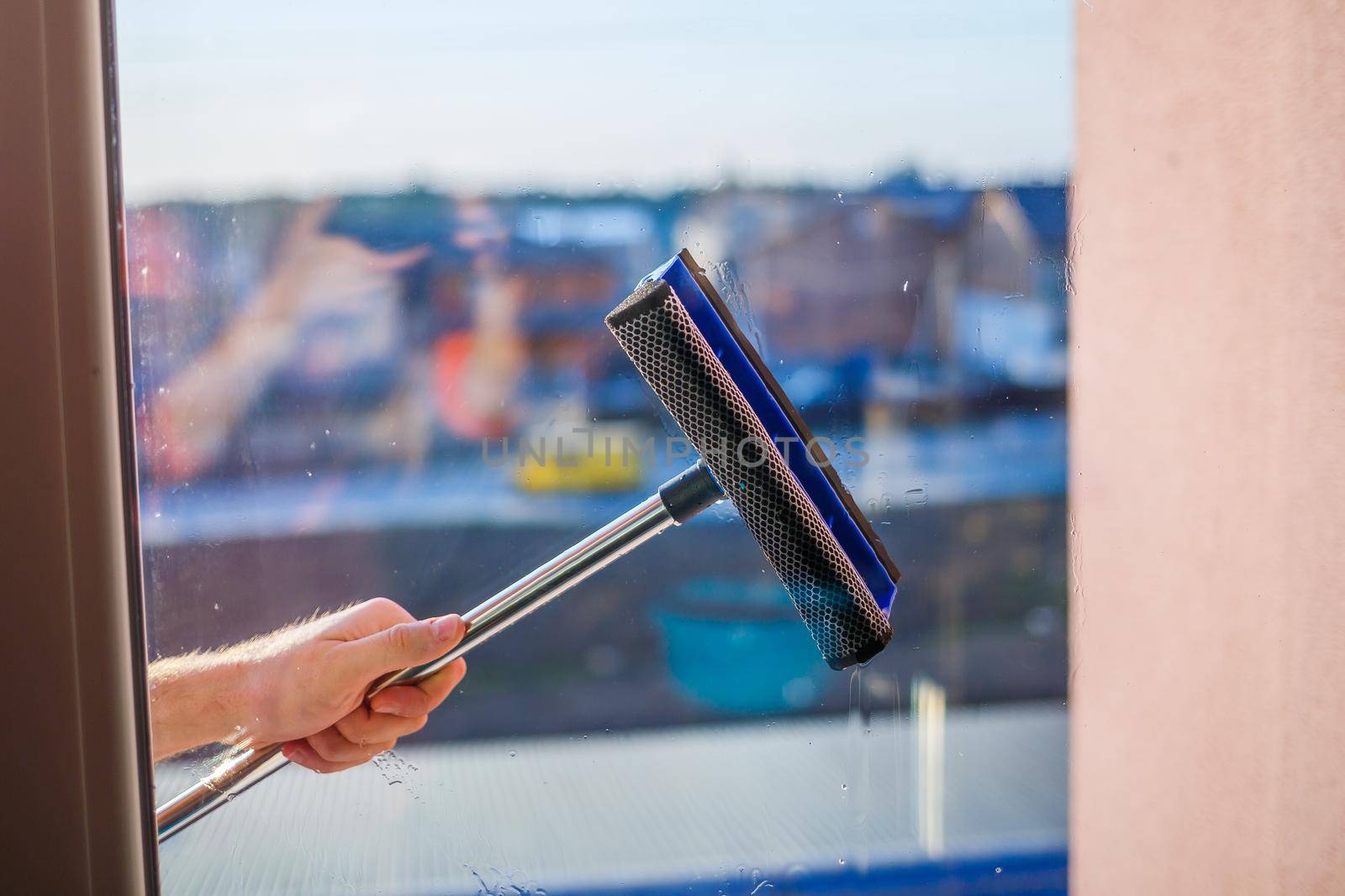 Window cleaning in high-rise buildings, houses with a brush. Window cleaning brush. Large window in a multi-storey building, cleaning service. Dust removal and glass washing.