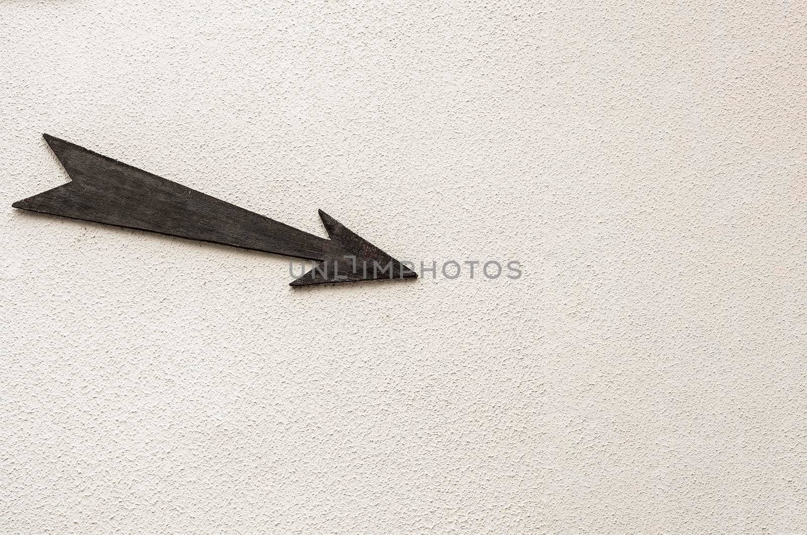 Wooden arrow pointer to the right down on light background. Copy space