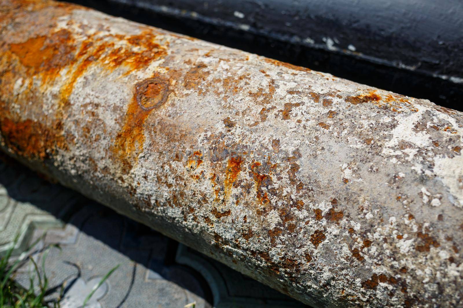 a large metal rusty pipe lies on concrete